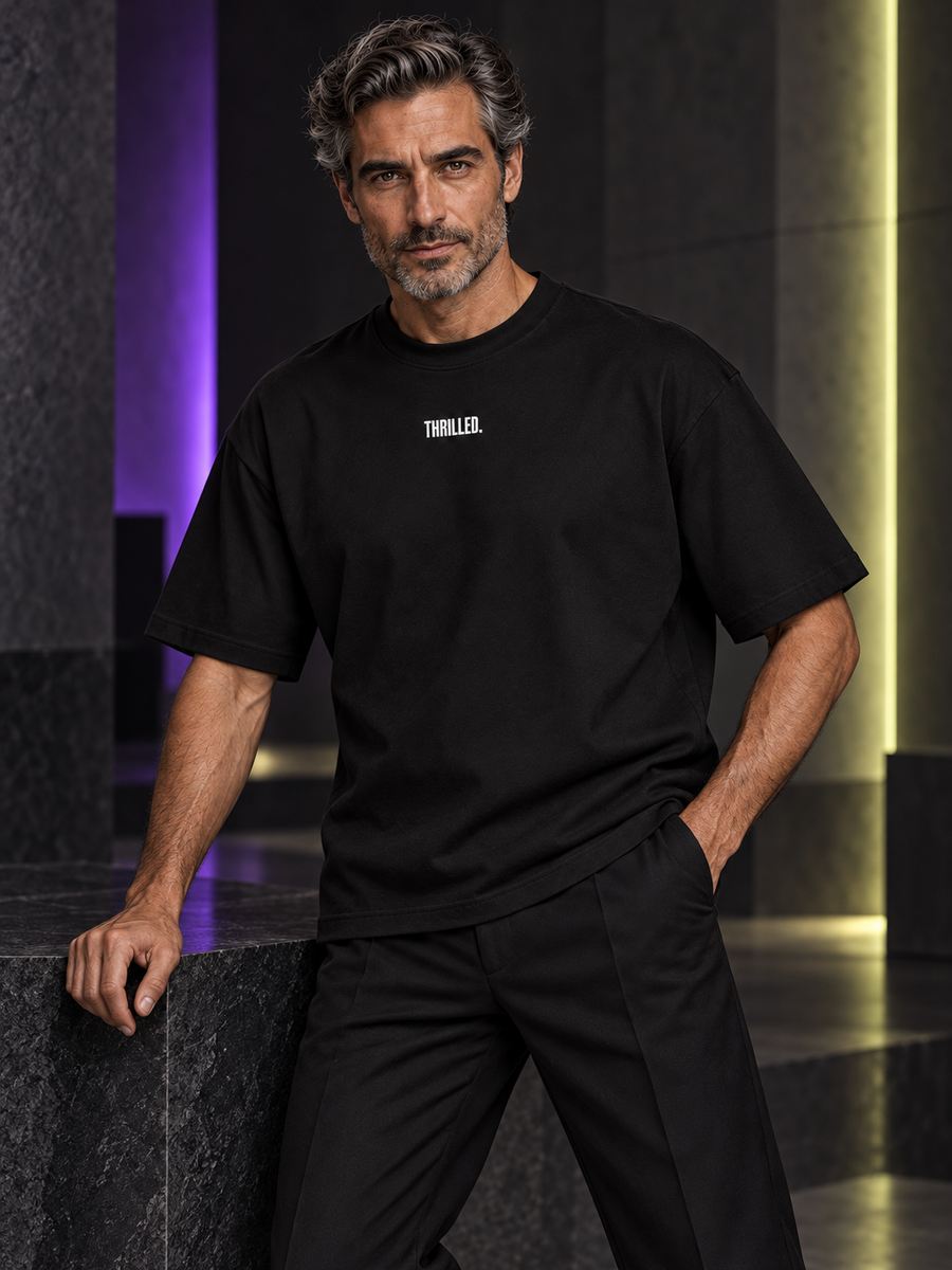 WRYKIND editorial — Magazine-style AI styling image of a male model posing in the THRILLED. black tee